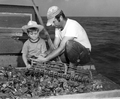 A boy watches his father shucking oysters on a boat - Apalachicola, Florida