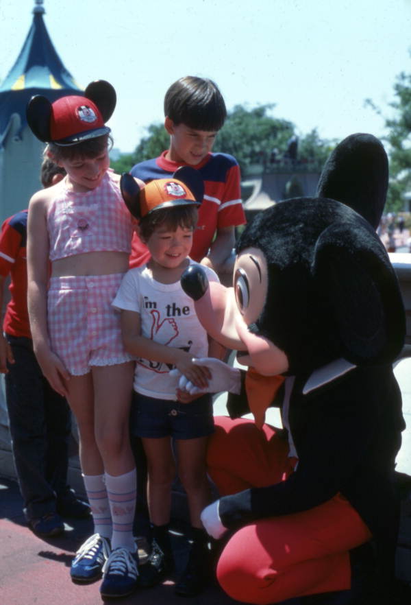 Mickey Mouse greets several children at the Magic Kingdom, part of Walt Disney World (1977).