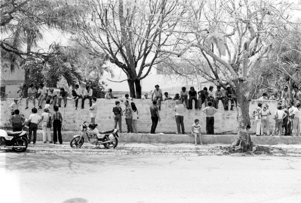 Family and friends of Cuban refugees arriving from Mariel wait outside of the Key West Latin Chamber of Commerce of the Lower Keys, located in the old United Services Organization (USO) building at the intersection of Southard and Whitehead Streets. In Key West, approximately 150 local volunteers and medical staff--including physicians from the medical branch of the Cuban Confederation of Professionals in Exile and several nurses from a Cuban nursing home in Hialeah--worked in shifts to operate a 24-hour infirmary and processing center for incoming Marielitos, which provided medical care, food, and clothing. Photograph by Dale McDonald, 1980.