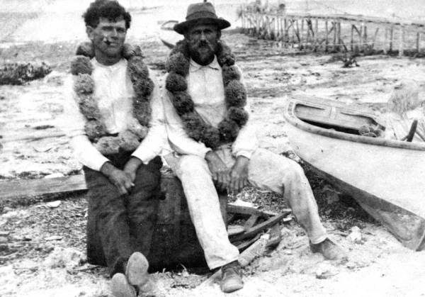 Two men wearing leis made from sponges - Plantation Key (circa 1910).