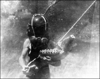 Diver holding lower jaw of mastodon (193-)