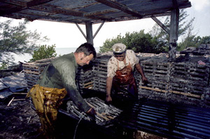 Captain Roche and mate Clyde Carey dipping a crawfish trap in creosote to protect it from rot: Stock Island, Florida (1974)