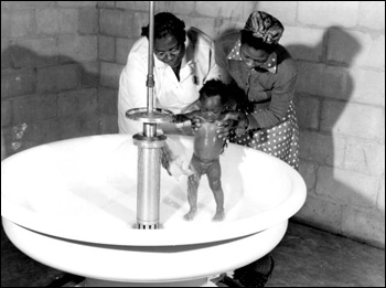 Baby being given a shower at a migrant labor camp: Belle Glade, Florida (1941)