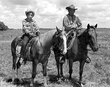 Seminole Indian cowboy Charlie Micco and grandson Fred Smith on horseback in a cattle ranch: Brighton Reservation, Florida (1950)