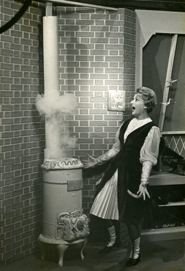 Miss Nancy stands next to a magical pot-bellied stove in her store, ca. 1966. The stove's smoke transported children into an alternative world filled with music and moving pictures. Other props included a 