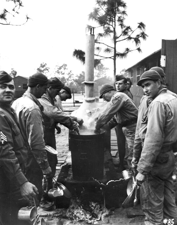 Camp residents wash their mess kits in a pot of boiling water after a meal at Camp Gordon Johnston (circa 1943).