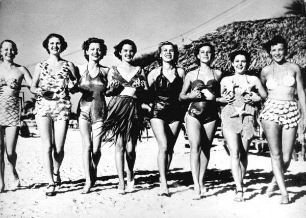 Ladies pose on Miami Beach wearing swimsuits made of straw, tarpon shell, gold mesh, palm fronds, alligator hide, rubber, coral, starfish, and seashells (1937).