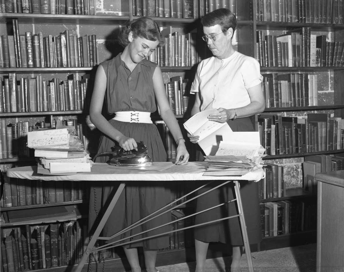 Dr. Dorothy Dodd and unidentified student flattening documents