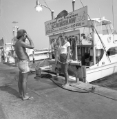 A man taking a picture for a young woman in front of a charter boat - Destin, Florida