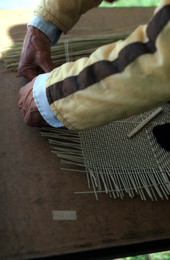 Tuyen Pham tying together pieces of whittled wood to make a basket - Pensacola, Florida.