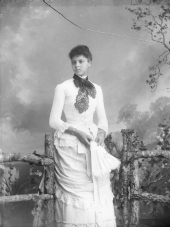 Young African American woman wearing a dress and holding a feather fan.