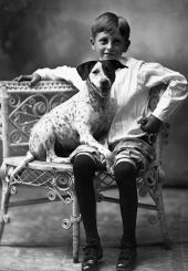 Boy posed with dog on wicker chair