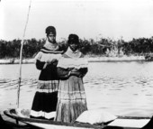 Two Seminole women standing in a canoe