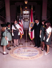 Secretary of State Tom Adams pointing out features of the State Seal on the capitol floor to some girl scouts.